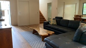 Ein Wohnzimmer mit Sofa, Couchtisch und einer Treppe, die in einen anderen Raum führt.