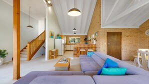 A spacious living area with a sofa, coffee table, and a kitchen in the background. - Seahorse On Fawcett- by Lifestyle Brunswick Heads (BRUNSWICK HEADS)