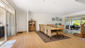 A dining area with a wooden table and wicker chairs, a cabinet with glass doors, and a view through a glass door to an outdoor patio.