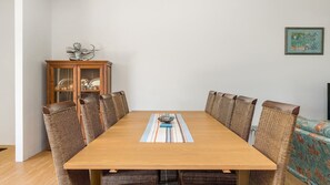 A dining area with a wooden table, wicker chairs, a cabinet with glass doors, and a framed picture on the wall.