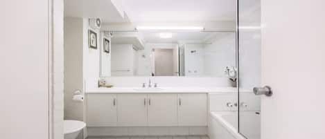 A modern bathroom with a white sink, mirror, and shower.