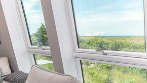 A room with large windows, a view of greenery and a distant landscape.