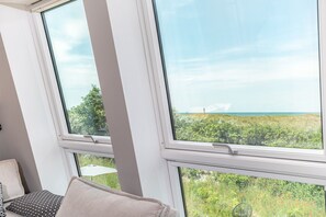 A room with large windows, a view of greenery and a distant landscape.