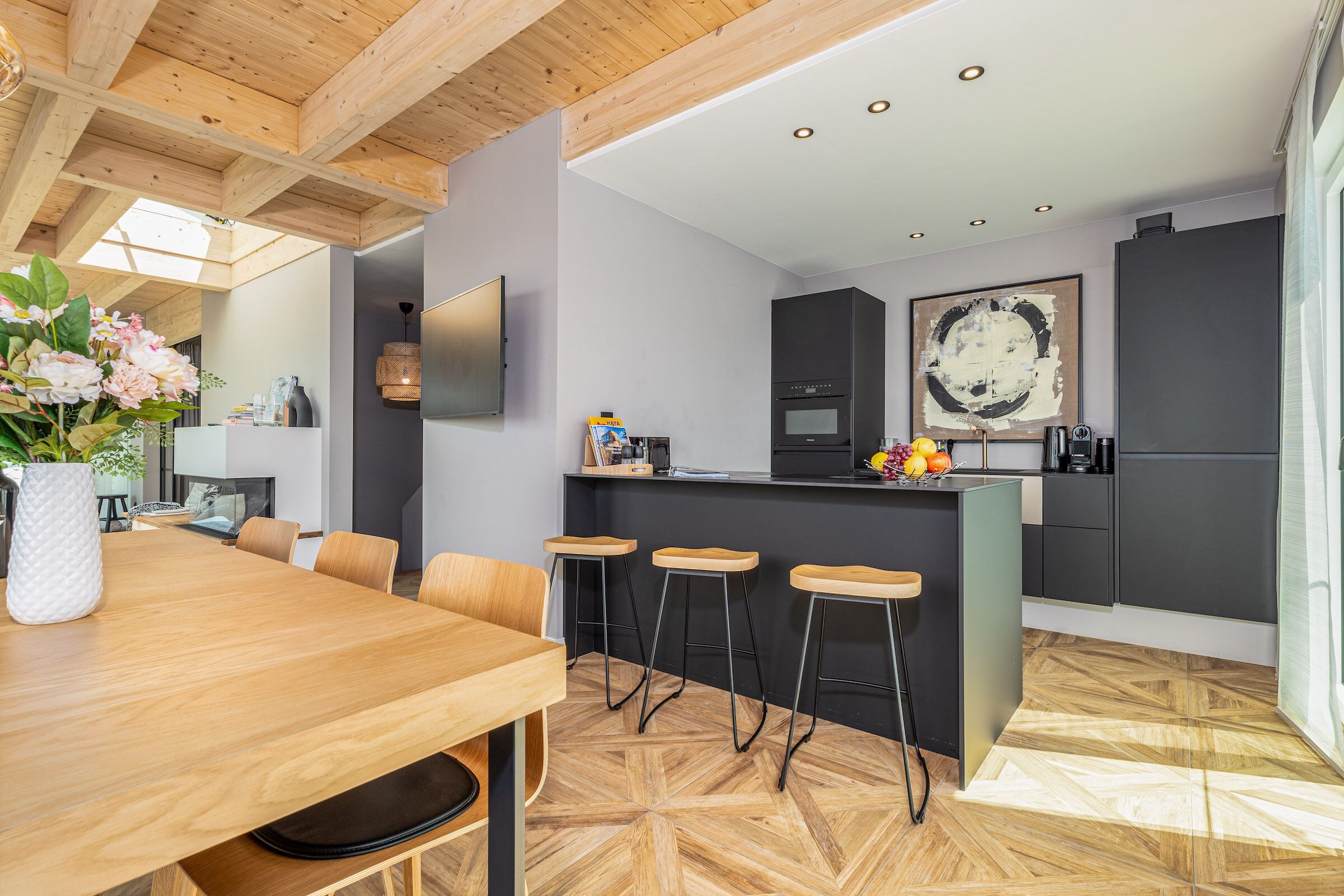 Een moderne keuken met een houten eettafel, barstoelen en een groot schiereiland.