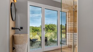 A modern bathroom with a large glass door leading to a patio area.