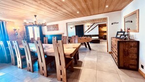 Ein geräumiger Essbereich mit einem Holztisch und Stühlen, einem Kicker und einer Treppe, die zu einer oberen Ebene führt.