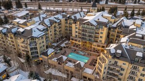 Et hotel med flere etager og en central gårdsplads med swimmingpool, omgivet af altaner og en stolelift i baggrunden.