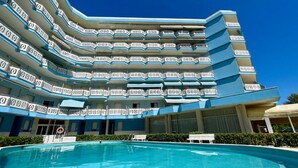 Um hotel de vários andares com uma piscina em primeiro plano.