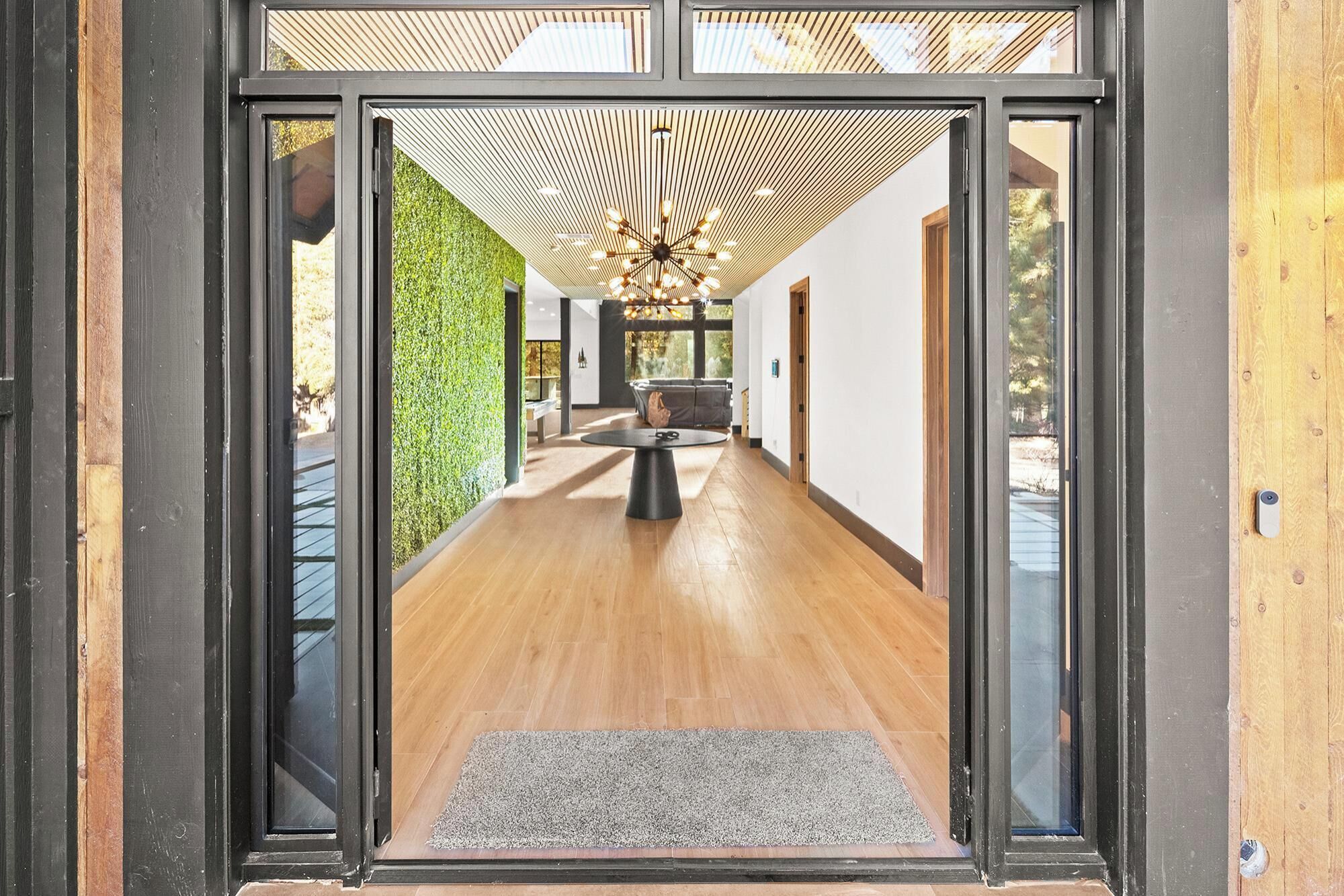 Un interno moderno con pavimento in legno, parete verde e lampadario particolare.