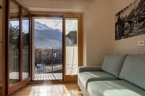 Ein Zimmer mit einer Schiebeglastür, die auf einen Balkon mit Bergblick führt.