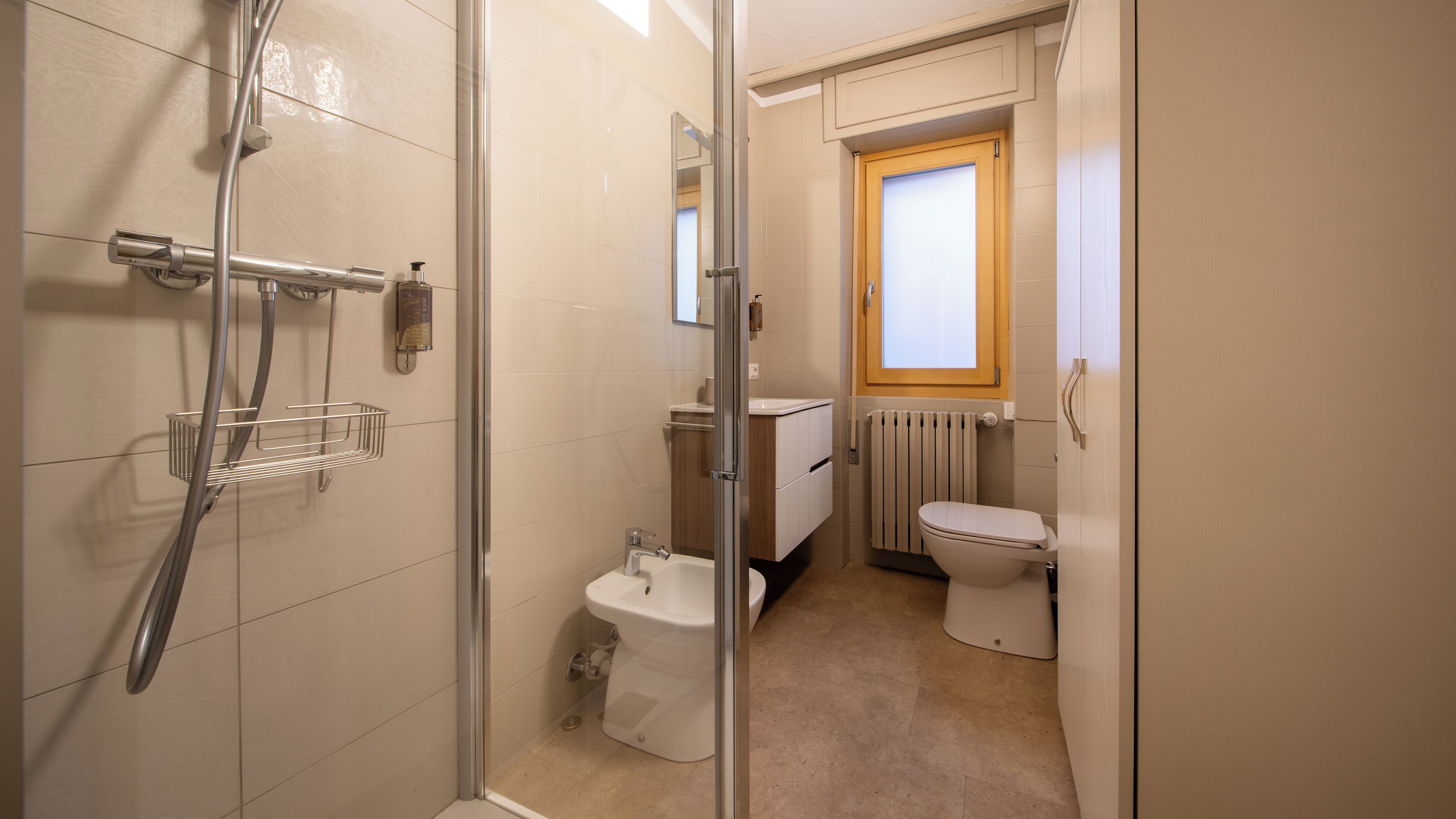 A bathroom with a shower, toilet, and bidet.