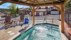 A covered outdoor swimming pool with wooden deck seating and a metal fence.
