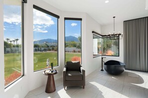 A modern interior with large windows, a black chair, and a unique black bowl-shaped seating. - $5M PV Estate|Casita|Camelback View|Sleeps 16 (Paradise Valley)