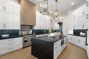 A modern kitchen with white cabinets, a black marble island, stainless steel appliances, and pendant lighting. - $5M PV Estate|Casita|Camelback View|Sleeps 16 (Paradise Valley)