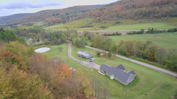 An aerial view of a rural property with a large house, a pond, and surrounding fields.