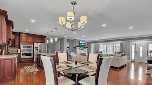 A spacious kitchen with wooden cabinets, a central island, and a dining area with a glass table and chairs. - Ellicottville Chalet & Cottage 5 Mi to Village (Salamanca)