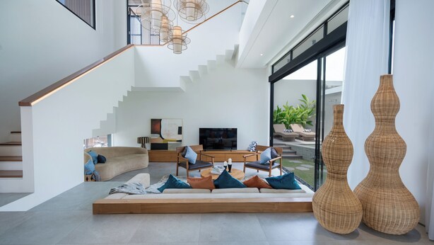 A modern living room with a sofa, chairs, a coffee table, and a TV. There is a staircase leading to another level. - Uma Namu Villa by Betterplace (Canggu)
