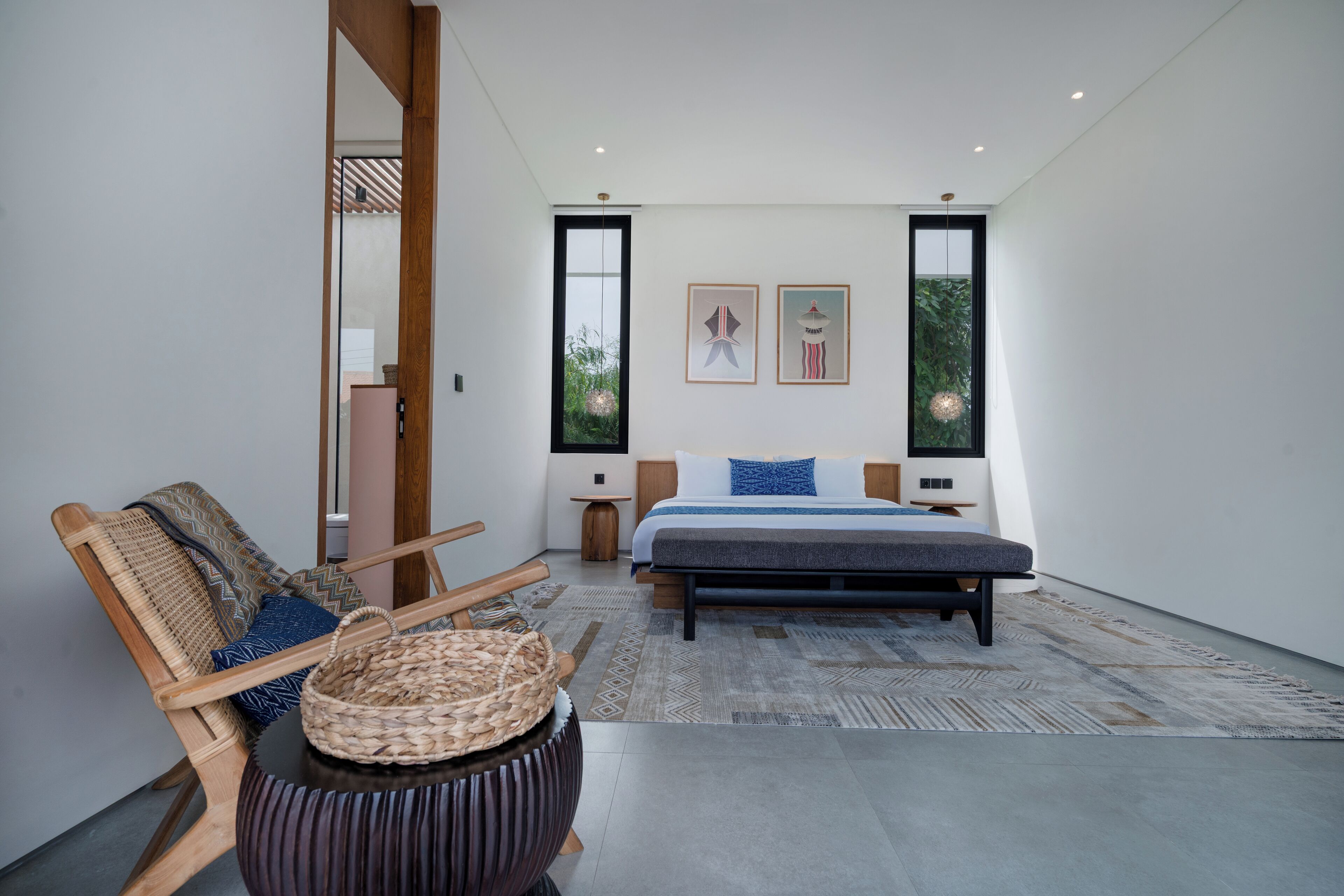 A modern bedroom with a large bed, a wooden chair, a small table, and two framed pictures on the wall.