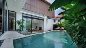 A modern house with a swimming pool, large windows, and a wooden deck. - Uma Namu Villa by Betterplace (Canggu)