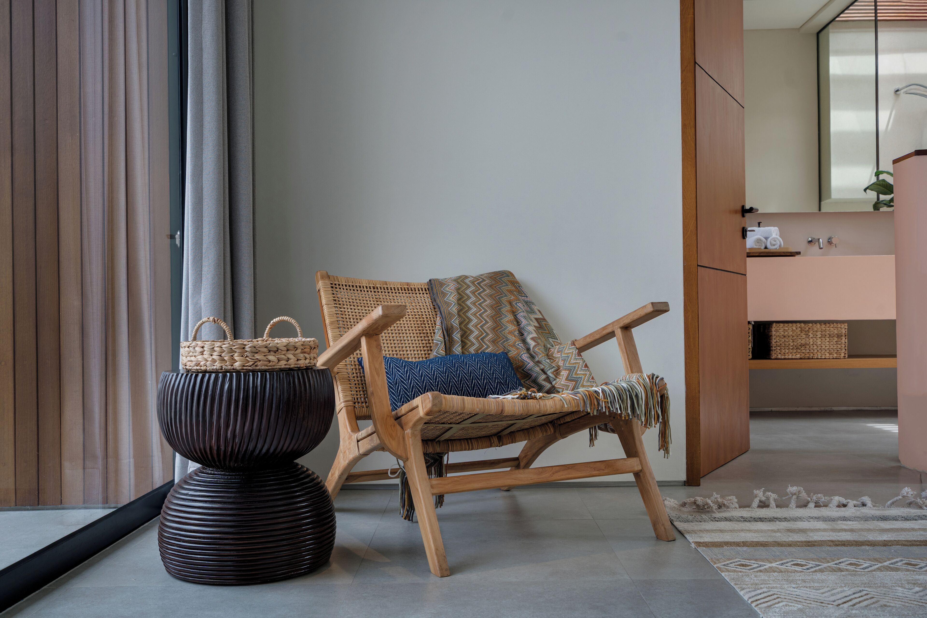 A room with a wooden chair, a woven basket, and a textured vase.