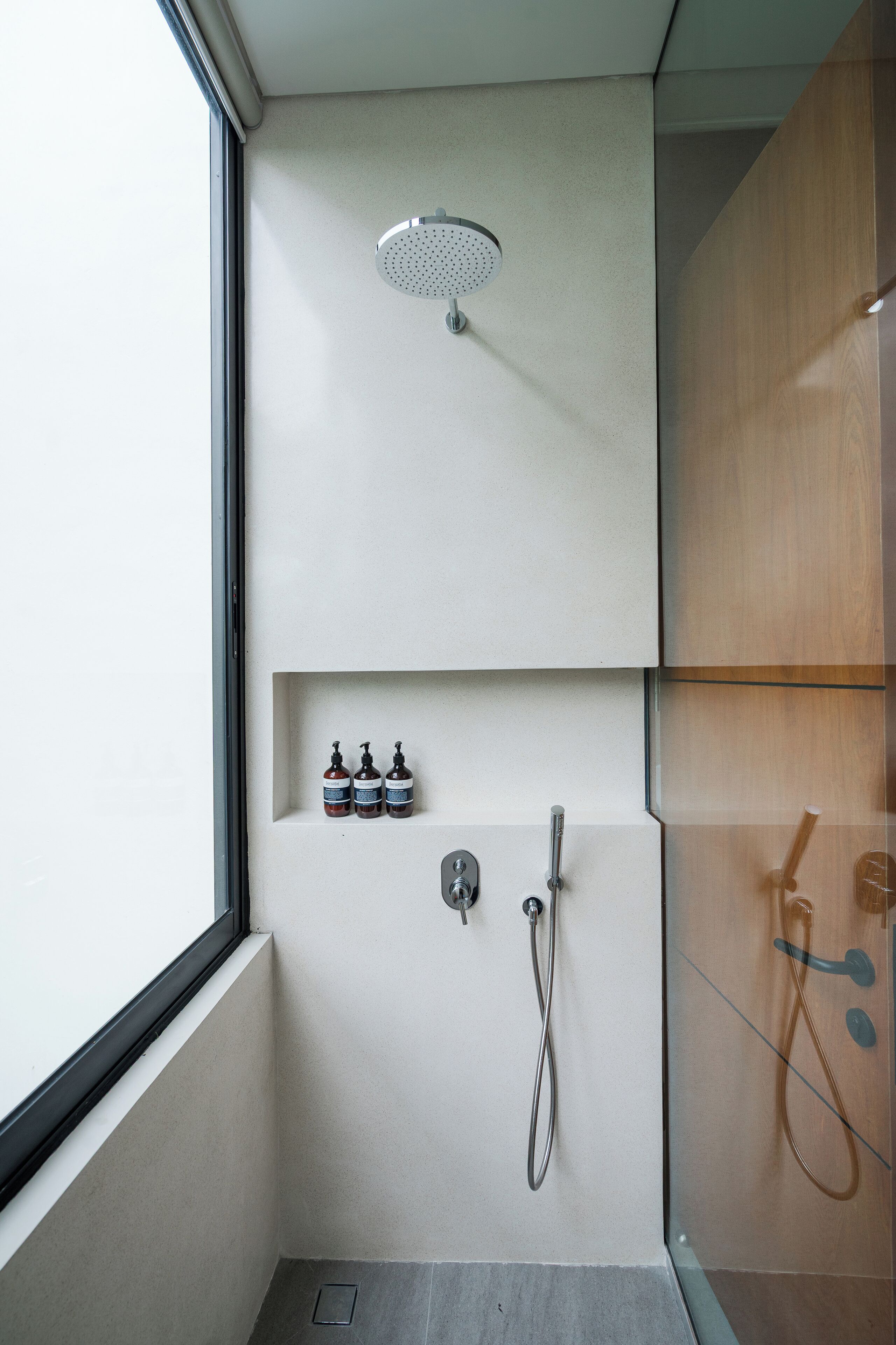 A modern shower with a glass enclosure, a built-in shelf with toiletries, and a visible showerhead.