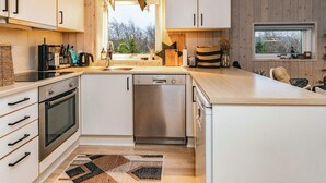 A modern kitchen with white cabinets, a dishwasher, and a large island. - 5 Person Holiday Home in Brovst (Brovst)