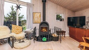 A cozy living room with a fireplace, a television, and a large window overlooking greenery. - 5 Person Holiday Home in Brovst (Brovst)