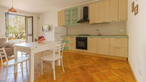 A modern kitchen with white cabinets, a black stove, and a tiled floor. - House The Seagulls - 4. Trilo 6 Sunset (Puglia)