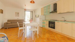 A compact living space with a kitchenette, a dining area, and a sofa. - House The Seagulls - 4. Trilo 6 Sunset (Puglia)
