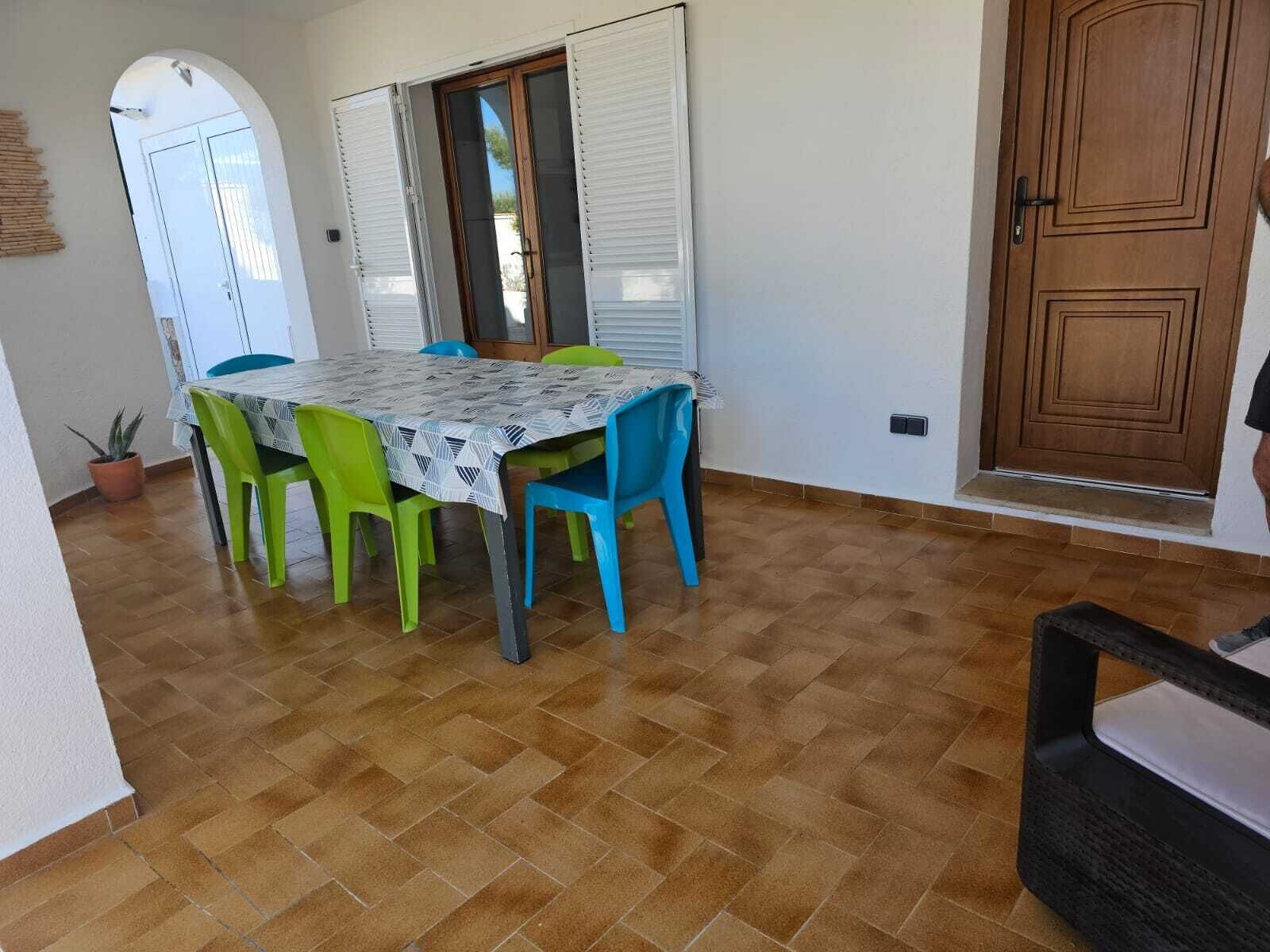 A dining area with a table and chairs, a wooden door, and a tiled floor.