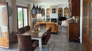 Ein großzügiger Wohnbereich mit Esstisch, Sofas und Kamin.