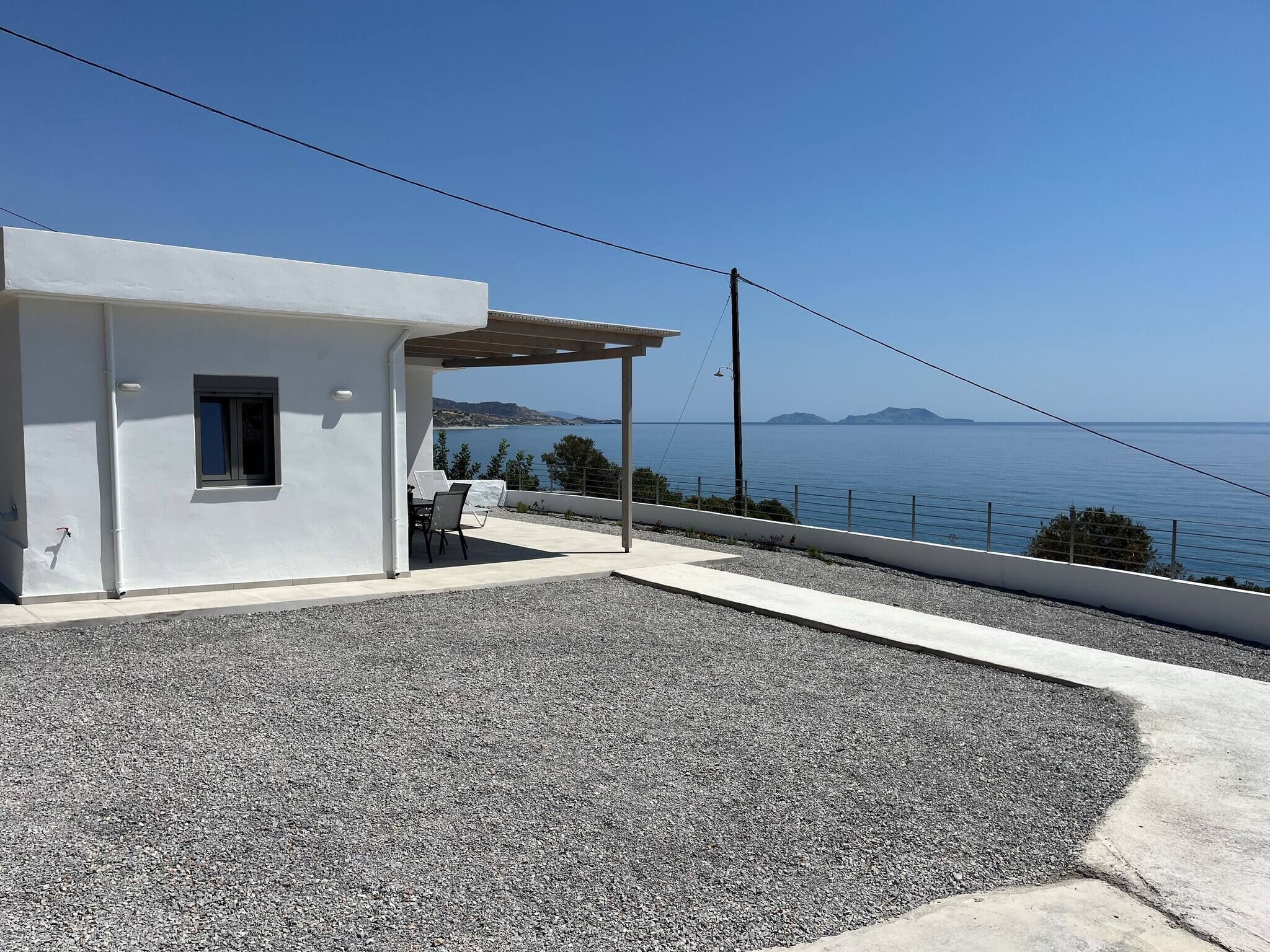 Ein modernes, weißes Gebäude mit einer überdachten Außenbestuhlung und Blick aufs Meer.