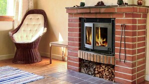Ein gemütliches Zimmer mit Kamin aus Backstein, einem gepolsterten Sessel und Holzboden.