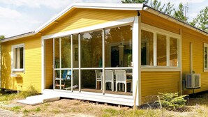 Ein gelbes Einfamilienhaus mit Veranda, großen Fenstern und einem kleinen Vorgarten.