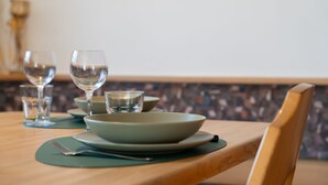 A dining table with a green placemat, a bowl, a glass, and a fork.