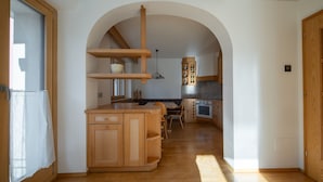 A kitchen with wooden cabinets, a dining area, and an arched doorway.