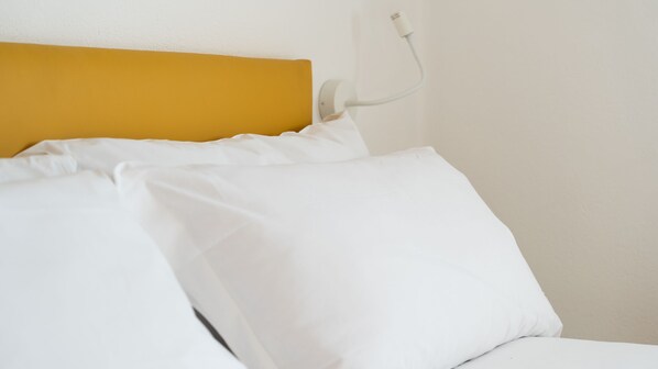 A bed with white bedding and a yellow headboard.