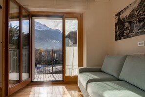 A room with a sliding glass door leading to a balcony with a view of mountains and a town. - Milano 20 in Bormio With 1 Bedrooms and 1 Bathrooms (Bormio)