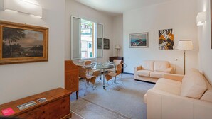 Un salon comprenant un coin repas, un canapé, un meuble en bois et des œuvres d’art accrochées aux murs.