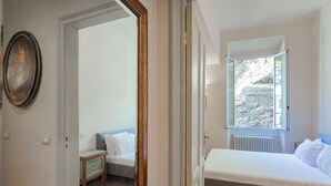 Une chambre à coucher comprenant un lit, une table de chevet, un miroir et une fenêtre donnant sur un paysage rocheux.