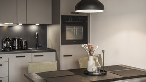 A modern kitchen with a dining table, a pendant light, and a vase with flowers. - Apartment in Kirchberg Near Schaterzlift (Kirchberg in Tirol)