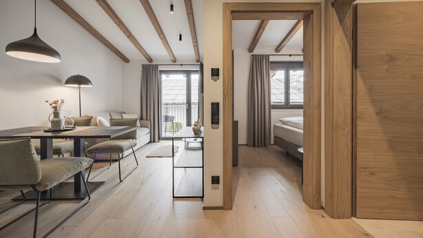 A modern interior with a dining area, a sofa, and a bed in a hallway. - Apartment in Kirchberg Near Schaterzlift (Kirchberg in Tirol)