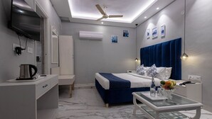 A modern hotel room with a bed, bedside table, desk, and a ceiling fan. - Hotel Downtown (Chandigarh)