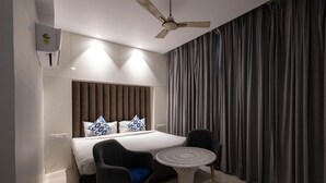 A modern hotel room with a bed, a ceiling fan, a small round table, and a large window with curtains. - Hotel Downtown (Chandigarh)
