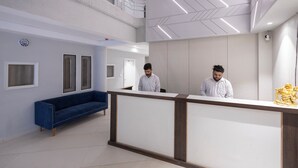 A modern reception area with a high ceiling, a blue sofa, and a reception desk. - Hotel Downtown (Chandigarh)