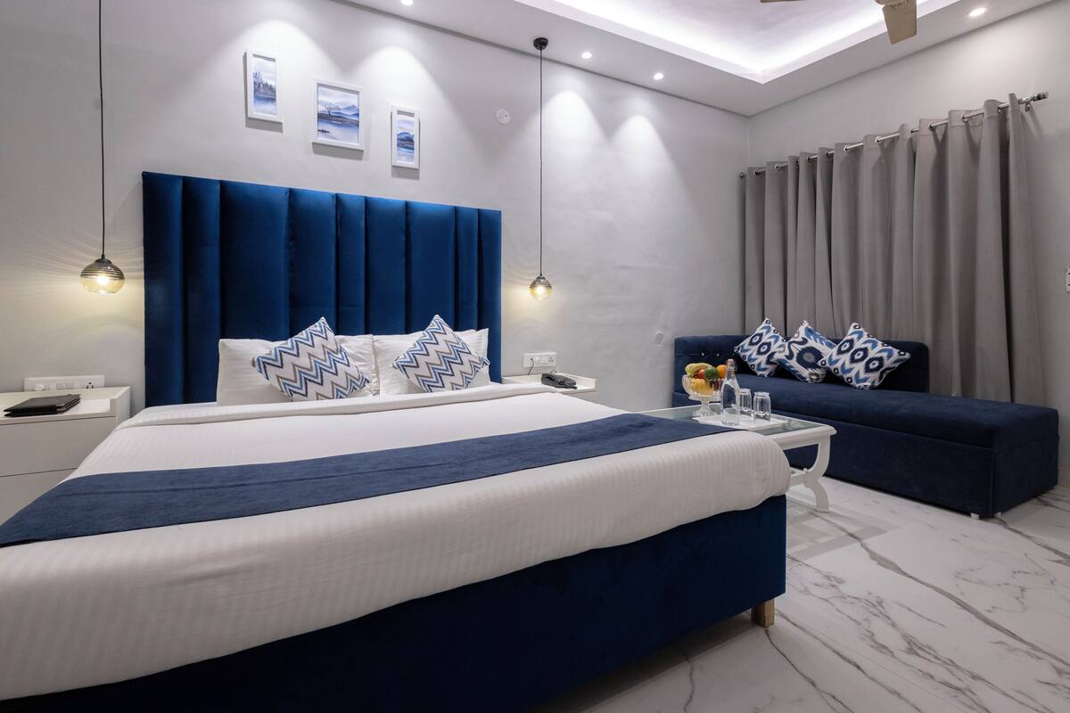 A modern bedroom with a large bed, a sofa, and a nightstand.