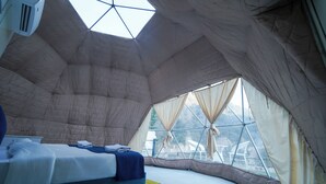 A spacious tent with a large bed, a window, and a ceiling fan. - Kylo Resort (Atali)