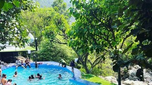 A swimming pool surrounded by lush greenery, with people swimming and relaxing. - Kylo Resort (Atali)