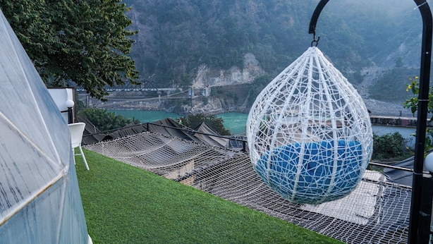 A hanging chair in a netted area with a view of a mountainous landscape and a river. - Kylo Resort (Atali)