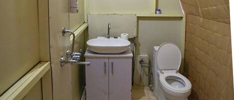 A compact bathroom with a toilet, sink, and shower.